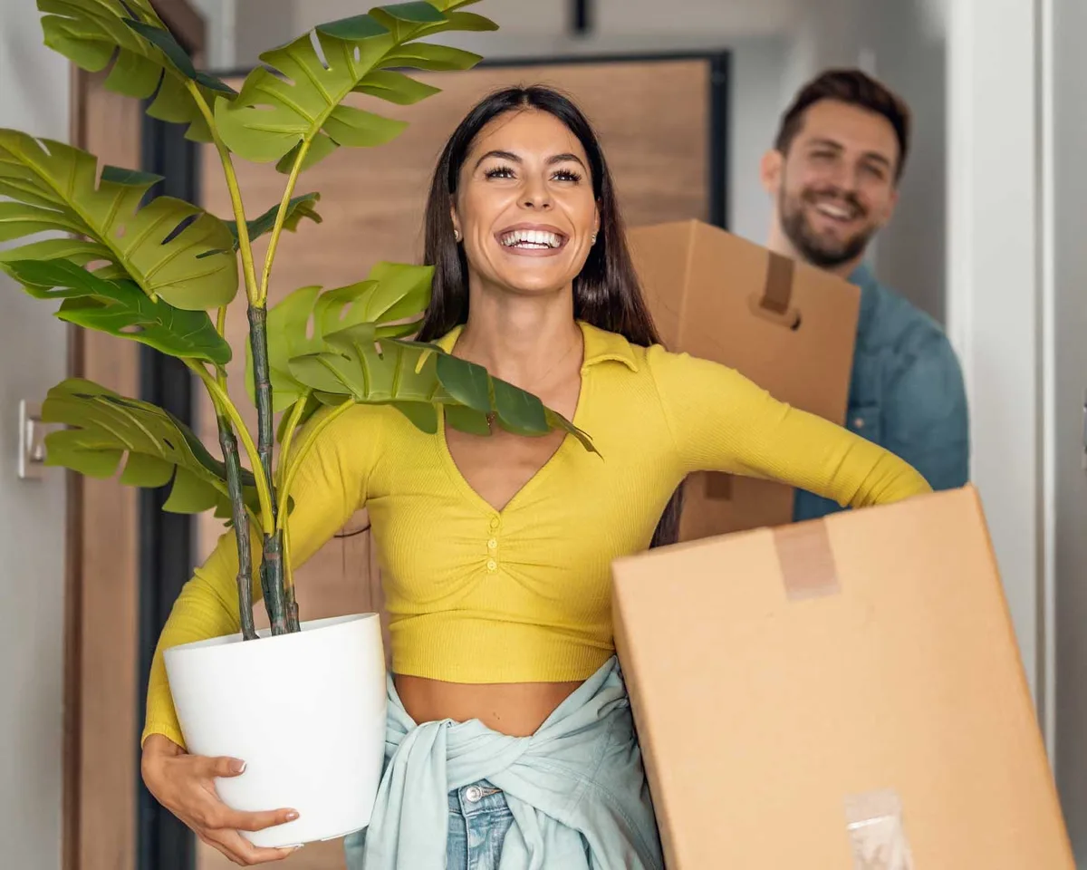A happy couple carrying boxes into their new home